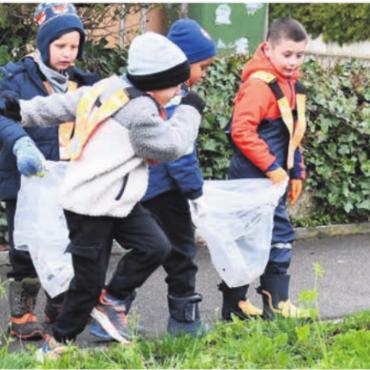 Mit gutem Beispiel voran - Die Kinder sind mit viel Eifer dabei, jeden «Fötzel» auf dem Weg zu finden. Bild: mo