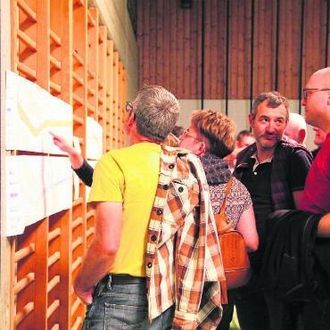 Keine Luxuslösung geplant - Die aufgehängten Pläne werden von den Anwesenden genaustens studiert. Nicht alle haben Freude am Projekt. Bild: Monica Rast