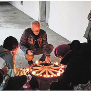 Weihnachtliche Motive erkundet - Benno Seiler, Bildmitte, und die Besucher des Rundgangs entzünden die Kerzen des Adventskranzes in der ursprünglichen Form, mit Kerzen für jeden Tag.
