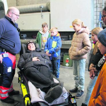 Mit Blaulicht und Sirene - Sven Rohner lässt die Kinder auf der Trage Probe liegen. Bilder: Monica Rast