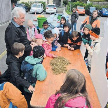 Damit Kühe nicht sterben müssen - Landwirt Alois Horat zeigt den Schulkindern, was er alles im Gras findet, das er frisch geschnitten hat. Bilder: Chregi Hansen