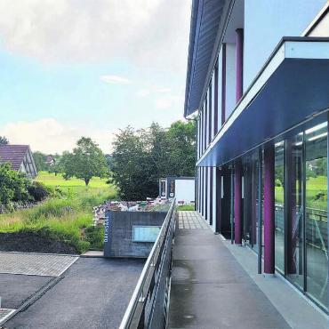 Diskussionen sind vorprogrammiert - Einer der möglichen Standorte ist die Wiese direkt hinter dem Gemeindehaus – also ungefähr dort, wo sich derzeit der Container für die Bauarbeiten auf dem Parkplatz befinden. Bild: Chregi Hansen