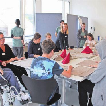 «In ein Wespennest gestochen» - Pascale Iten, Berufsbildnerin Service, zeigt den Schülern, wie man aus einer Serviette eine Krone faltet.