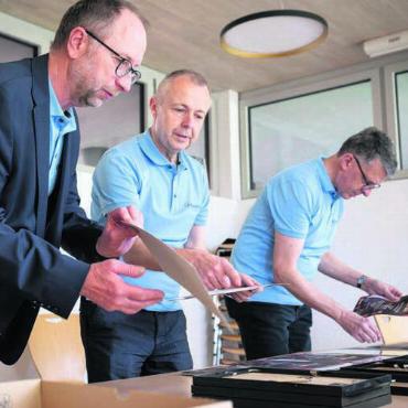 Musik baut Brücken - Die Kiwanis-Mitglieder Beat Koch, Alex Meyer und Tobias Knecht bereiten die Urkunden für die jungen Musiker vor. Bild: ibw / Felix Wey