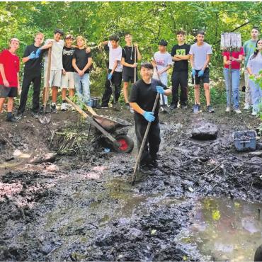 Den stinkenden Brei entfernt - Die Schülerschaft (hier eine Klasse der Realschule) packt an beim verschlammten Bünzi-Biotop. Bild: zg