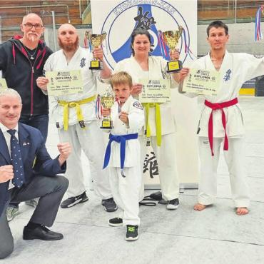 Mutter und Sohn feiern - Wohler Karatekas präsentieren mit Freude die erkämpften Trophäen am Trimmiser Cup. Von links: Erich-Andreas Bürgisser (Coach, mit Pokal von Musaro), Peter Andrasi, Finn Schwenkfelder, Yvonne Schwenkfelder, Kashmir Islami. Kniend: Raphael Gauch (Schiedsrichter). Bild: zg