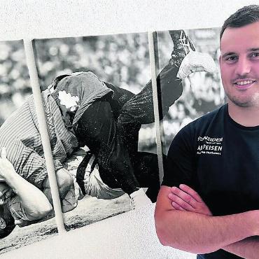 Bevor er noch durchdreht - Bereit für grosse Taten. Joel Strebel steht vor dem Bild, das einen seiner grössten Würfe zeigt: den Sieg gegen Königsanwärter Samuel Giger am ESAF 2022. Bild: spr