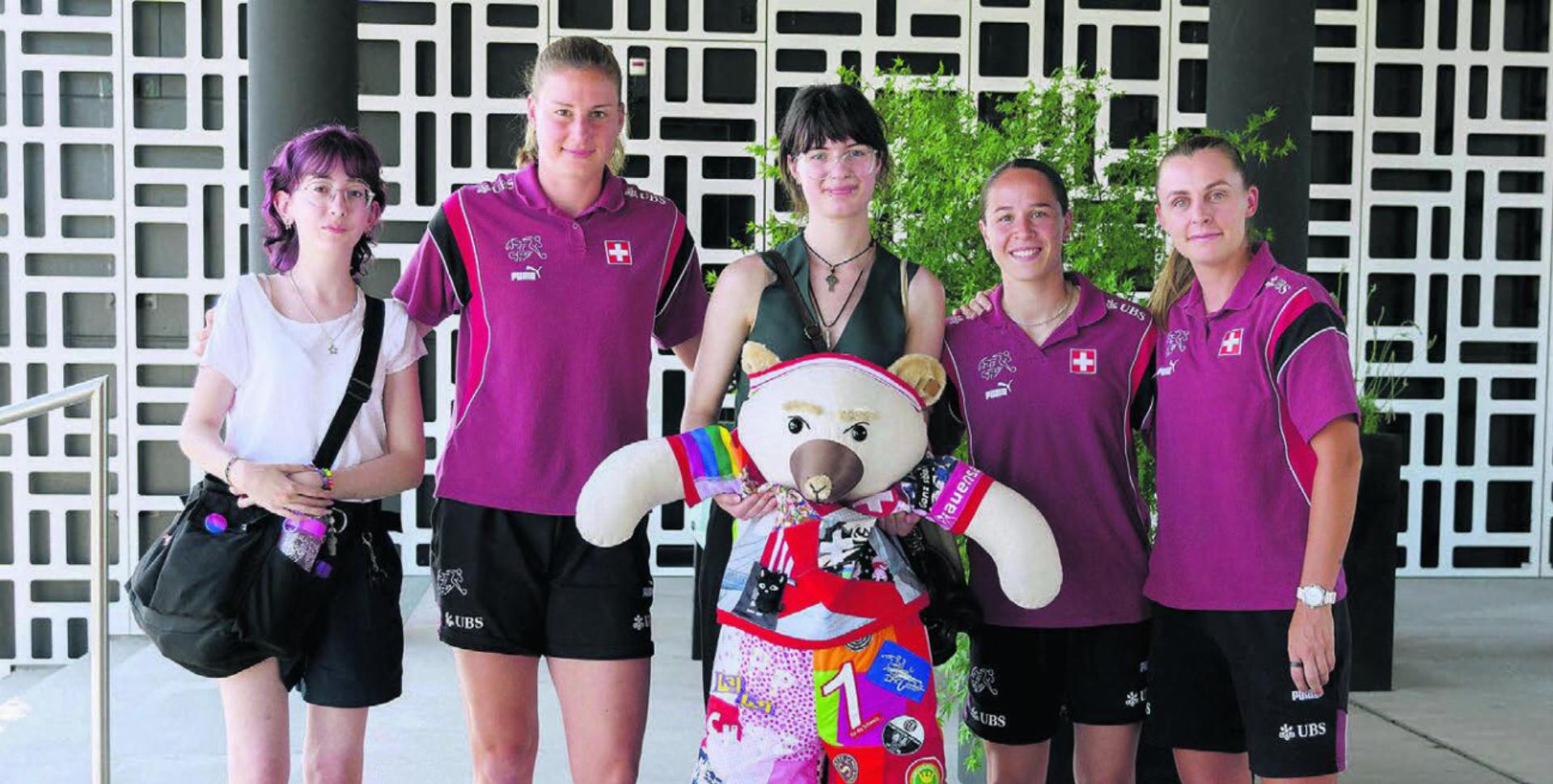 Die Übergabe von Teddy «Helva» an die Nati. Die Lernenden Elena (links) und Danielle mit den Nati-Spielerinnen Julia Stierli, Géraldine Reuteler und Noelle Maritz (von links). Bild: SRF