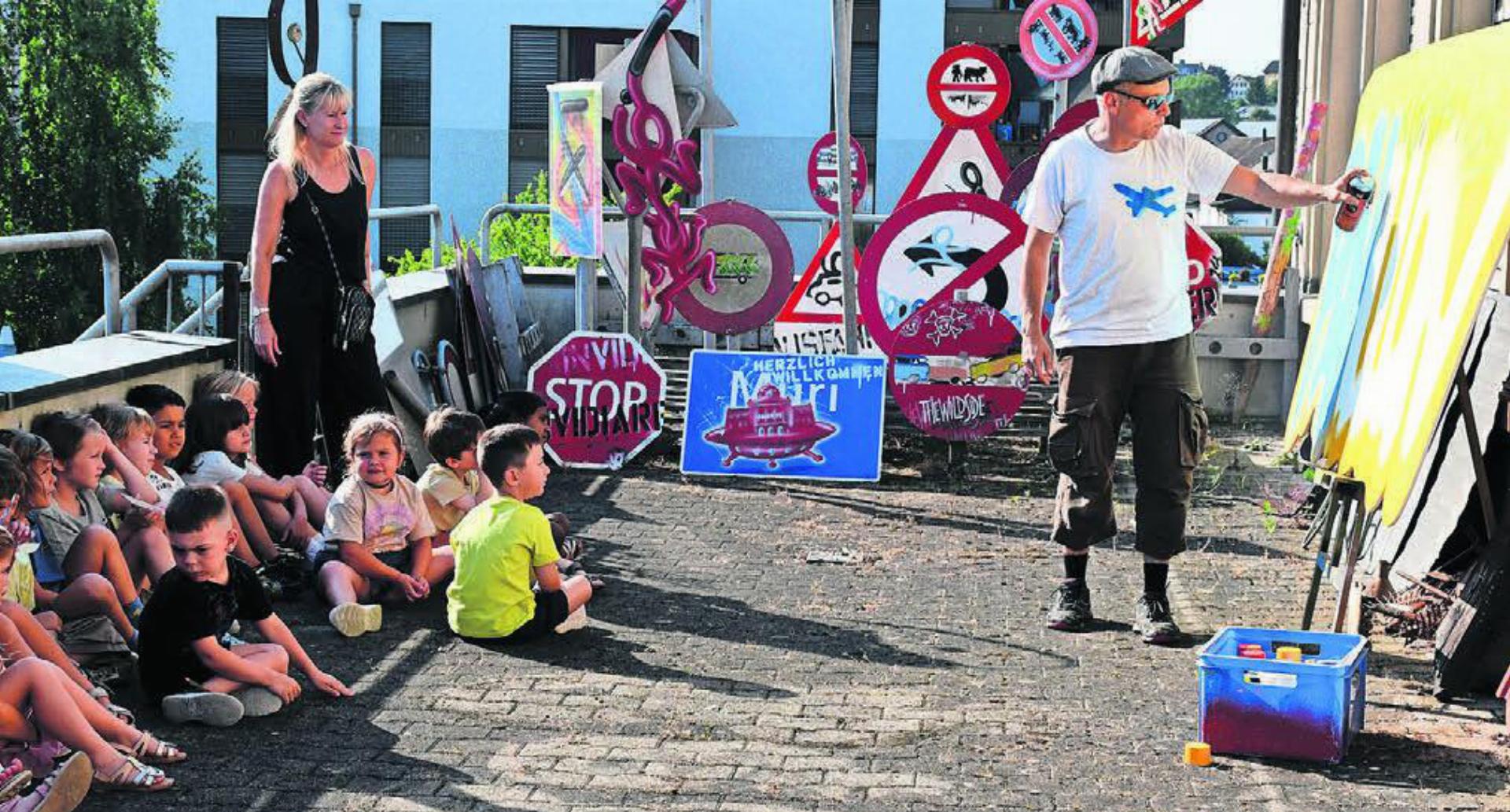 Im Schatten der Terrasse verfolgen die Kindergärtler fasziniert, wie aus einer weissen Wand ein Kunstwerk mit wird.