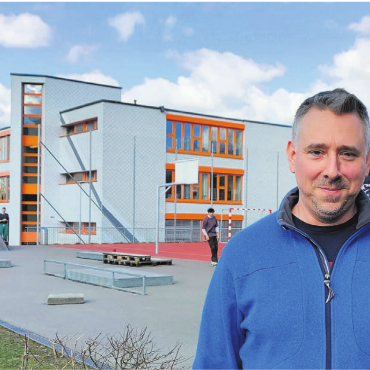 Dietrich gegen die Hitze - Stefan Dietrich vor dem Isenlauf-Schulhaus. Während er sich im Winter hier pudelwohl fühlt, wird es im Sommer zuweilen unangenehm heiss. Bild: huy/Archiv