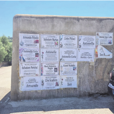 Verabschiedung auf Sardisch - Bild: vaw

Bosa ist ein malerisches Städtchen am westlichen Ufer von Sardinien. Am Stadtrand des pittoresken Ortes steht diese Mauer. Sie schafft Aufmerksamkeit und das nur wenige Schritte neben der belebten Hauptgasse der Altstadt. Dort geniessen die Touristen den Charme des Ortes mit den vielen farbigen Häusern und das feine Essen in der Strassengastronomie. An dieser Mauer geben die Einheimischen bekannt, dass ihre Lieben verstorben sind.