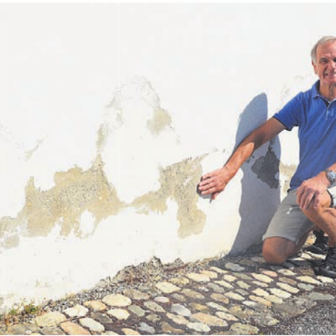 Wieder mehr Bedeutung geben - Franz Rutzer zeigt die abblätternde Farbe an der Fassade. Dies geschieht, weil die Feuchtigkeit an den Wänden nach oben steigt.
